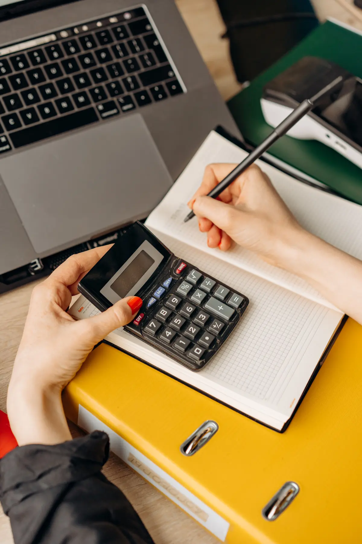 Calcul d'un devis à la calculatrice, à côté d'un ordinateur portable