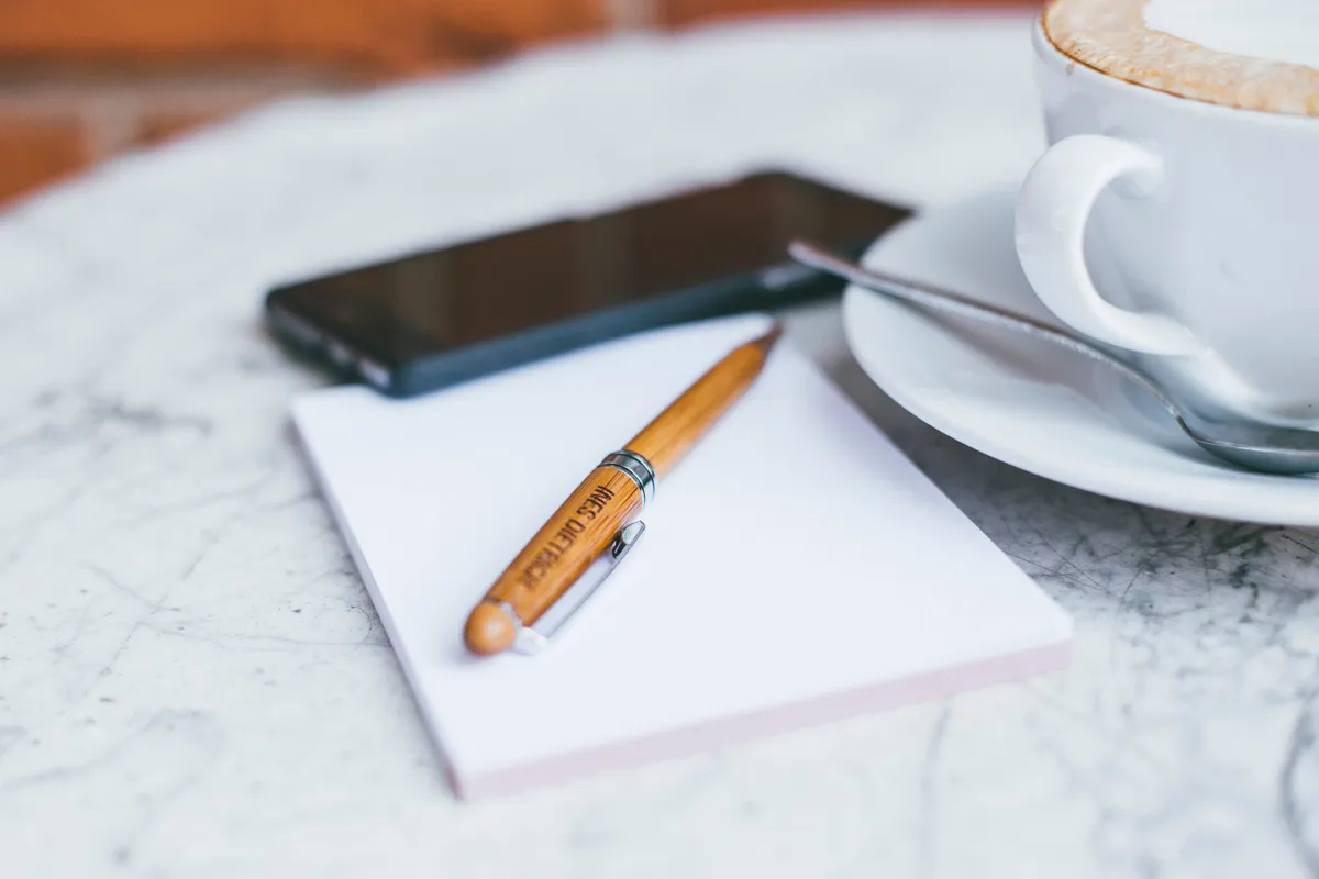 Bloc-notes, stylo et café sur une table, prêts pour un rendez-vous