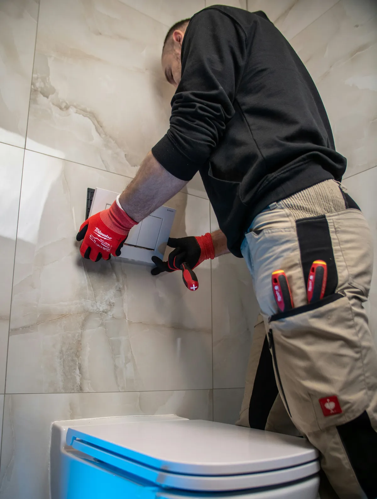 Installation du mécanisme de chasse d'eau derrière une plaque murale, WC suspendu au premier plan
