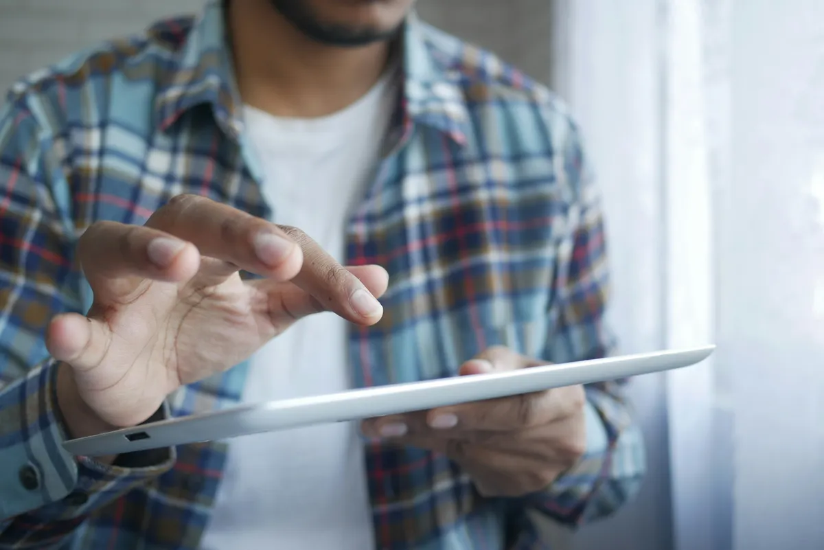 Main qui touche l'écran d'une tablette tactile